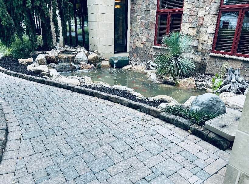 Koi pond with spillway bowl and waterfall at a commercial entrance walkway