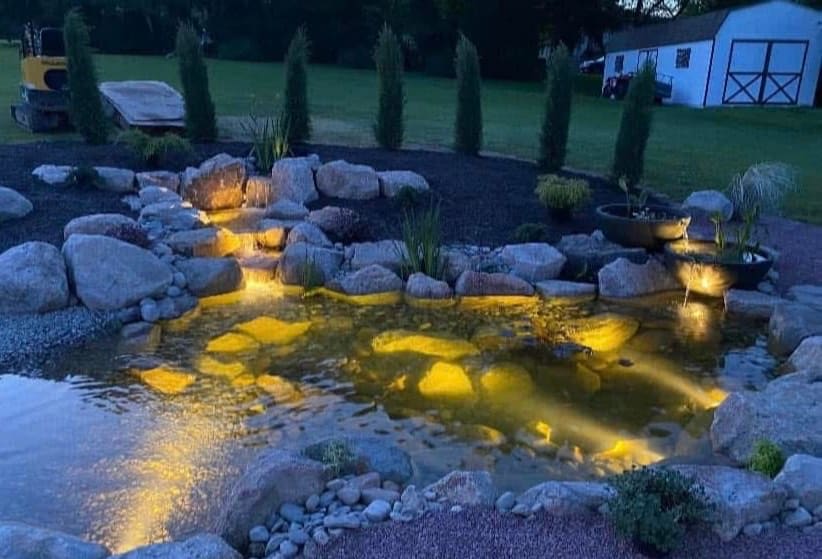 Ecosystem pond with waterfall and spillway bowls lit at dusk in Carbon County, PA