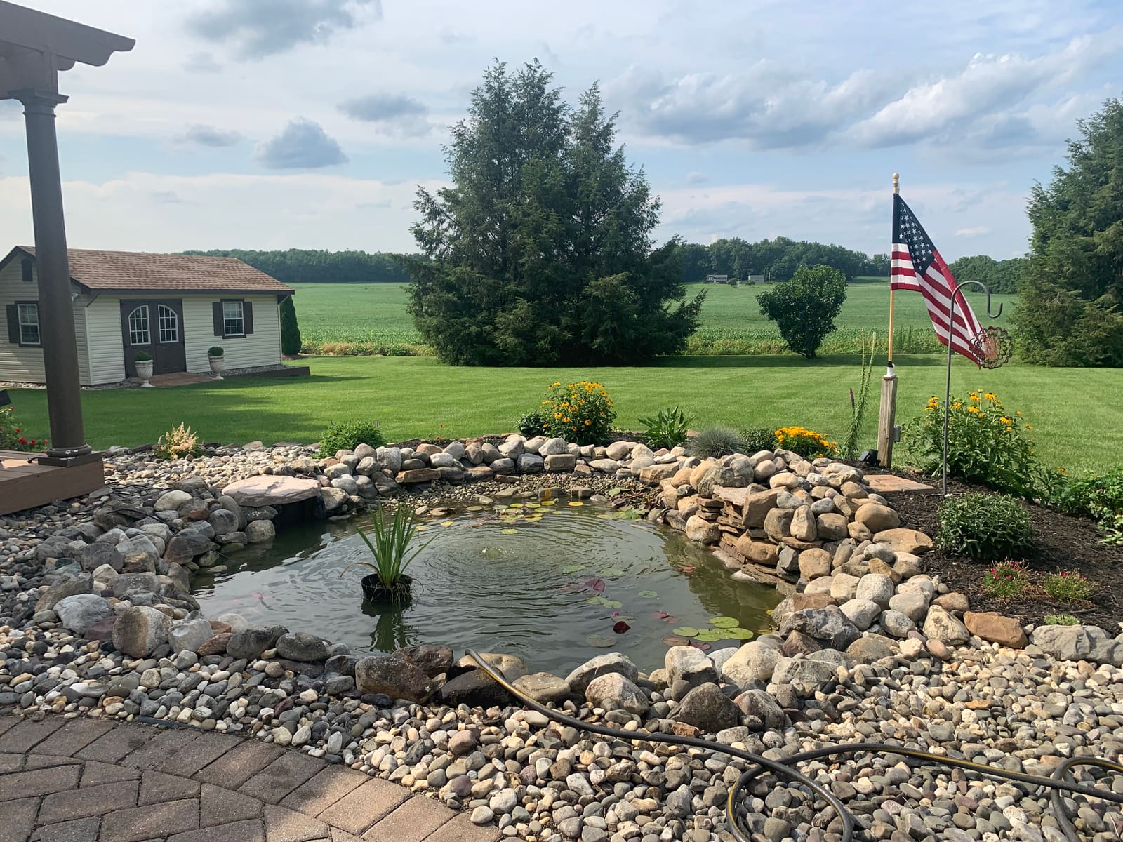 Pebble-beach ecosystem pond with waterfall overlooking farm fields near the Poconos