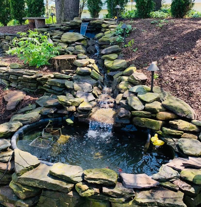 Terraced stacked-stone waterfall and stream dropping into a small round pond
