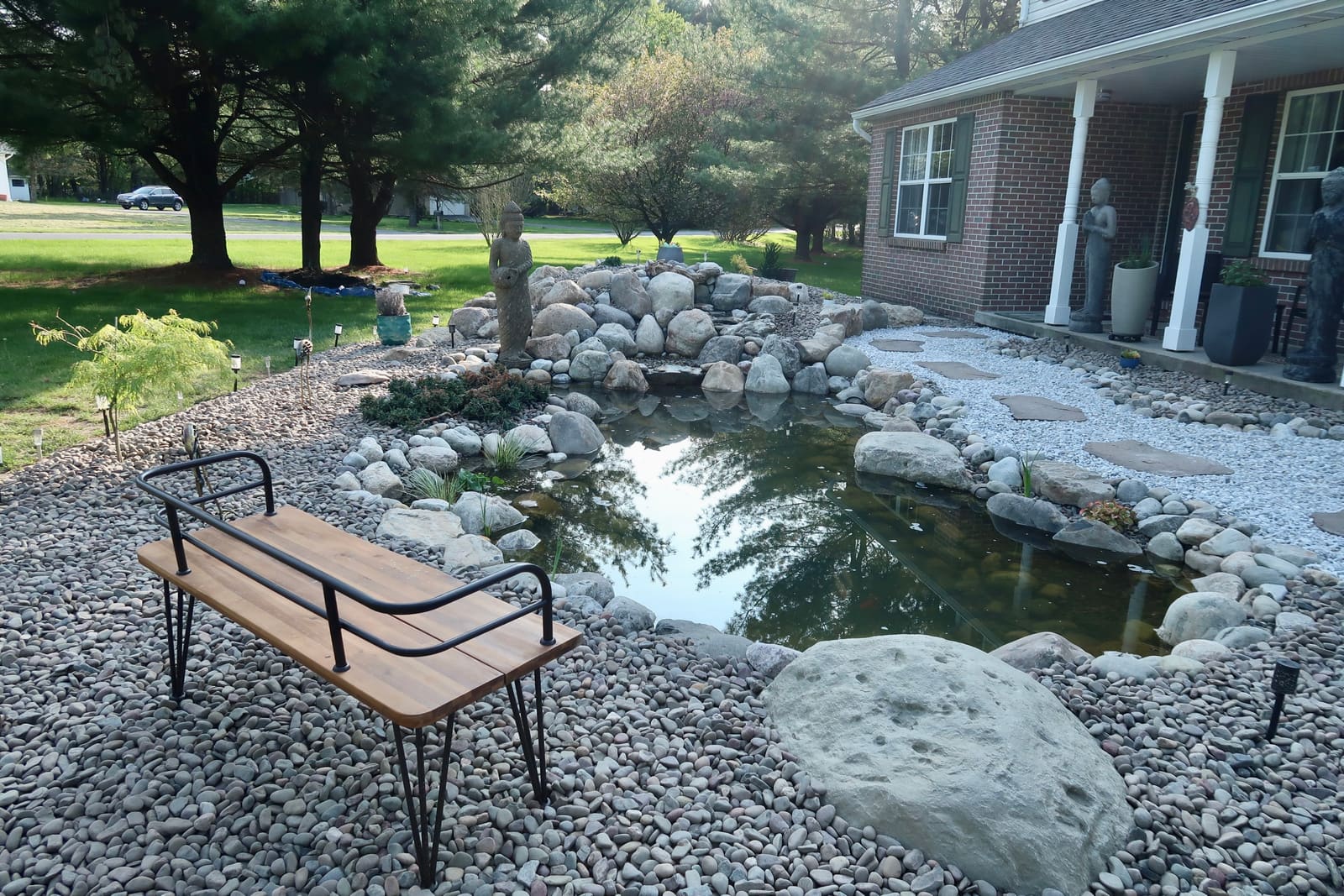 Zen front-yard pond with Buddha statue, boulder waterfall, and bench in Lehighton, PA